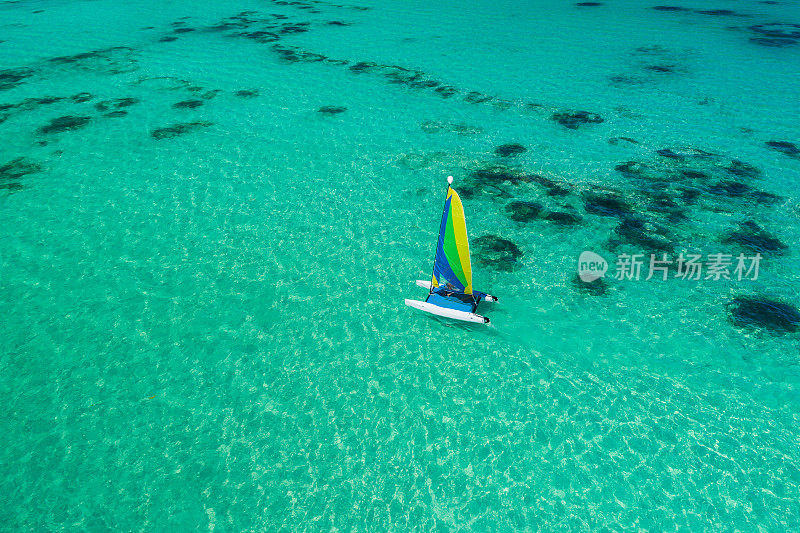 航拍无人机的航行帆船冲浪或双体船在蓝绿色的水附近的加勒比海Punta Cana海滩。